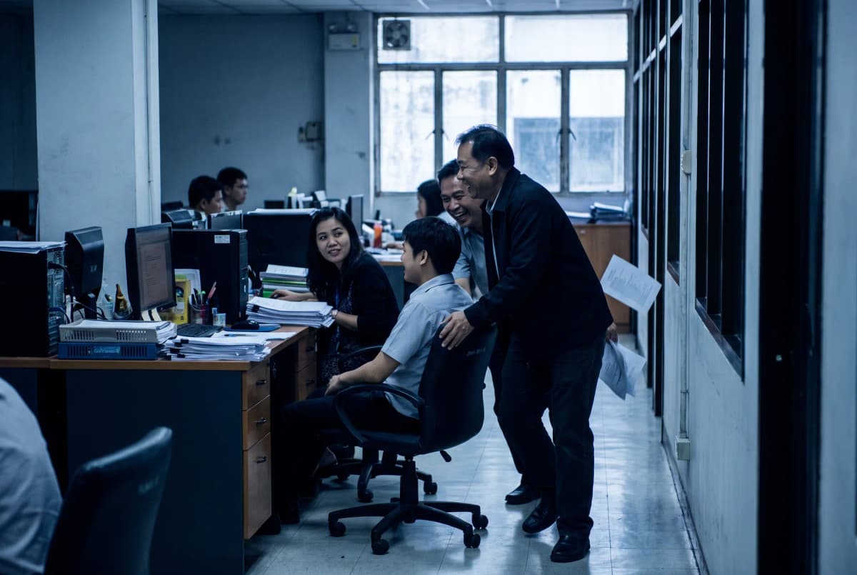 เพื่อนร่วมงานหัวเราะกันระหว่างเข็นเก้าอี้สำนักงานผ่านทางเดินระหว่างโต๊ะทำงาน