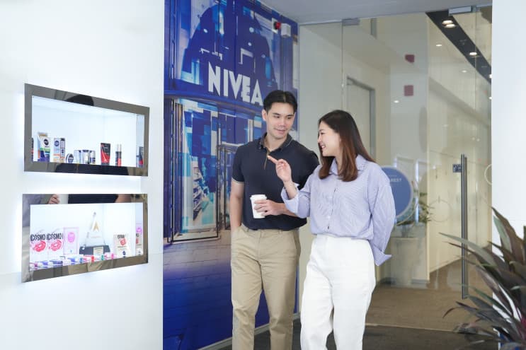 Designing Your Work Life, Designing with care at Beiersdorf ออฟฟิศที่ใช้ “CARE” ออกแบบการทำงาน - เมื่อเข้าไปที่ Beiersdorf พื้นที่แรกที่คุณจะได้พบคือโซนต้อนรับ พื้นที่เล็กๆ ที่ถูกออกแบบอย่างเรียบง่าย แต่เต็มเปี่ยมไปด้วยบรรยากาศสบายๆ อบอุ่น ให้ผู้มาเยือนรู้สึกผ่อนคลาย เป็นการเริ่มต้นวันด้วยพลังงานดีๆ ที่คอยโอบรับพนักงานเมื่อเดินทางมาถึงออฟฟิศแห่งนี้ ซึ่งนอกจากจะเป็นพื้นที่ต้อนรับแล้ว ยังมีโต๊ะเก้าอี้สำหรับ Co-working Space อยู่ใกล้ๆ ให้พนักงานสามารถมานั่งจิบกาแฟ พูดคุย ปรึกษางานต่างๆ เป็นความเรียบง่ายในการออกแบบที่ไม่ต้องการให้พนักงานรู้สึกตึงเครียดในการทำงาน แต่ต้องการให้พนักงานได้เข้ามาทำงานแบบเป็นกันเอง เป็นเจ้าของพื้นที่การทำงานร่วมกัน สามารถเลือกพื้นที่ทำงานได้ เป็นอิสระ และใกล้ชิดกัน