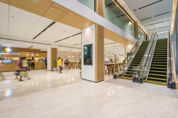 ทัวร์ BJC Big C ออฟฟิศในฝัน สร้างสรรค์ชีวิตที่ดีกว่าเพื่อทุกคน - ไม่แปลกใจ ว่าทำไมที่นี่ถึงเป็นที่ทำงานในฝันของใครหลายๆ คน เพราะแค่เดินเข้ามาที่ล็อบบี้ออฟฟิศของ BJC ก็ต้องว้าวกับดีไซน์ที่ดูทันสมัยและเรียบหรูมากๆ เป็นพื้นที่โซนแรกที่สร้างความประทับใจให้พนักงานและแขกผู้มาเยือนได้ไม่น้อย ถือเป็นการสร้างบรรยากาศก่อนการเริ่มงานได้ดีเลยทีเดียว
2. ห้องประชุมมากมาย
เรียกได้ว่าที่นี่มีห้องประชุมครบทุกแบบ ทุกขนาดที่พนักงานต้องการเลยทีเดียว จะประชุมเล็ก 2-5 คน หรือประชุมใหญ่ทั้งแผนกก็มีห้องไว้รองรับแบบไร้กังวล แถมเทคโนโลยีอำนวยความสะดวกอย่าง Projector, LCD Projector และ TV ก็มีไว้ให้พร้อม เป็นไงล่ะ…ครบครันไปหมด
3. โซนล็อคเกอร์ประจำตัวสารพัดประโยชน์
ที่นี่มีล็อคเกอร์สำหรับพนักงานแต่ละคนให้สามารถใช้เก็บของส่วนตัว ของมีค่า หรือเอกสารต่างๆ ได้ พนักงานจะได้ไม่ต้องวางไว้ที่โต๊ะตัวเองให้กินพื้นที่ ช่วยเพิ่มพื้นที่ในการทำงานมากขึ้น โต๊ะโล่งก็รู้สึกสบายตา สบายสมอง ล็อคเกอร์ทุกช่องมีกุญแจล็อคอย่างปลอดภัยทำให้เรามั่นใจได้ว่าของของเรานั้นเก็บอยู่อย่างดีแน่นอน
4. พื้นที่ทำงานส่วนกลาง ไว้แชร์ประสบการณ์ร่วมกัน
ส่วนกลางที่ตกแต่งด้วยโทนสีน้ำตาลดูอบอุ่นและทันสมัย เก้าอี้นั่งสบายสุดๆ เป็นพื้นที่ที่ทุกคนสามารถมาใช้ได้เลย ใครนั่งทำงานบนโต๊ะเบื่อๆ จะเปลี่ยนบรรยากาศมานั่งทำงานตรงนี้ก็ได้ เป็นพื้นที่สำหรับสร้างสรรค์ไอเดียใหม่ๆ ในการทำงาน หรือจะนั่งพักผ่อนกับเพื่อนร่วมงานยามว่างก็ดี
5. โซนทำงานโล่งสบาย ให้ฟีลผ่อนคลายเหมือนทำงานที่บ้าน
บริเวณโต๊ะทำงานหรือโซนออฟฟิศเป็นส่วนที่สำคัญที่สุด เพราะพนักงานต้องใช้เวลาในพื้นที่นี้เป็นส่วนใหญ่ ที่นี่จึงออกแบบโซนนี้ให้มีพื้นที่กว้างขวาง ดูโล่งสบายตา ไม่อึดอัด มีแสงสว่างมากพอต่อการทำงาน ช่วยทำให้พนักงานทุกคนมีสมาธิกับการทำงานได้อย่างเต็มที่
6. กองทัพร้านอร่อย ที่ทานบ่อยๆ ก็ไม่เบื่อ
แน่นอนว่าพอหนังท้องตึง ไอเดียก็บังเกิด ของอร่อยและถูกสุขลักษณะจึงเป็นเรื่องที่สำคัญมากๆ ไม่ว่าจะเป็นอาหารตามสั่ง ก๋วยเตี๋ยวรสเด็ด ของทานเล่น หรือเครื่องดื่ม ที่นี่ก็มีครบ ไม่ต้องเดินออกไปด้านนอกให้ร้อน สะดวกสบายและประหยัดเวลาด้วยนะ
7. โรงอาหารสไตล์คาเฟ่ เก๋ไก๋ไม่ซ้ำใคร
นอกจากอาหารจะอร่อยแล้ว โซนที่นั่งในโรงอาหารยังจัดแต่งให้เป็นสไตล์คาเฟ่ด้วย ช่วยให้พนักงานผ่อนคลายได้ดีมากๆ นอกจากนี้ภายในก็ยังมีที่นั่งไว้รองรับคนได้เยอะ ไม่ต้องกลัวว่าเวลาพักเราจะมาแย่งที่นั่งกับใครเขาไม่ทันเลยล่ะ ที่นั่งก็มีหลายแบบหลายมุมให้เลือก ทั้งโซฟา โต๊ะกลม หรือโต๊ะสูง จะมานั่งทานคนเดียวหรือทานกับเพื่อนร่วมงานก็สามารถเลือกนั่งได้ตามใจชอบ เป็นอีกหนึ่งพื้นที่กระชับความสัมพันธ์กับเพื่อนร่วมงานได้ดีเลยทีเดียว
8. เติมพลังการทำงานได้ทั้งวัน ที่ร้านกาแฟวาวี
คนรักกาแฟห้ามพลาด ที่ตึก Big C มีร้านกาแฟวาวี (WAWEE COFFEE) กาแฟ “พรีเมี่ยมออร์แกนิก” จากไร่วาวี ไว้ให้เติมเอนเนอจี้ได้ทั้งวันเลย และใครจะรู้ว่านี่เป็นอีกหนึ่งธุรกิจของกลุ่ม BJC Big C ทำให้พนักงานที่นี่ได้รับส่วนลดพิเศษ และโปรโมชั่นอยู่บ่อยๆ นอกจากจะได้ดื่มกาแฟดีๆ แล้วยังได้ช่วยเหลือเกษตรกรและรักษาสิ่งแวดล้อมไปพร้อมกันอีกด้วย
9. ประชุมเครียดใช่มั้ย? โกโก้ดัทช์สักแก้วช่วยได้
มาทางฝั่งของตึก BJC ก็ไม่น้อยหน้า มีร้านโกโก้ดัทช์ คาเฟ่ไว้บริการ สายหวานแต่เข้มต้องห้ามพลาด เพราะที่นี่นอกจากจะมีโกโก้แท้100% จากประเทศเนเธอร์แลนด์แล้ว ยังมีโดนัทไว้ให้ทางคู่กัน ฟินได้ทั้งวันที่ล็อบบี้ตึก BJC
10. อีกมุมของล็อบบี้ออฟฟิศ Big C ที่สวยทันสมัย
อีกหนึ่งไฮไลท์สำคัญของตึก Big C ก็คือบันไดเลื่อนตรงล็อบบี้นี่แหละ ที่ทำให้ตึกดูโมเดิร์นขึ้นมากๆ ภายในยังถูกออกแบบด้วยโทนสีขาวสลับไม้ให้ดูสะอาดและสบายตา แถมตรงประตูทางเข้ายังมีร้านกาแฟวาวีไว้ให้พนักงานได้เติมพลังยามเช้า สาย บ่ายเย็นเลย พนักงานออฟฟิศอย่างเราถ้าได้กาแฟซักแก้วก็คงมีแรงทำงานไปตลอดทั้งวันแล้ว….จริงไหม?
11. โซน แชท&แชร์ ไอเดียให้พุ่งปรี๊ด
Co-working space ที่ดูผ่อนคลายด้วยพรมสีเขียวอ่อน ตกแต่งด้วยต้นไม้ และแสงไฟนวลๆ เป็นอีกหนึ่งจุดที่ให้พนักงานได้มานั่งแชร์ไอเดียใหม่ๆ กับเพื่อนร่วมงาน หรือใครจะอยากจะยกโน๊ตบุ๊คมานั่งทำงานตรงนี้ก็ได้ เผื่อจะปิ๊งอะไรใหม่ๆ มาอวดเพื่อน
12. โฟกัสกับตัวเองสักพัก ที่มุมทำงานส่วนตัว
มุมโต๊ะนั่งที่มีวิวเป็นกระจกที่สามารถมองเห็นได้รอบด้าน เหมาะกับการนั่งคิดอะไรคนเดียว ให้ได้นั่งทบทวนการทำงาน และโฟกัสกับงานมากขึ้น ยิ่งได้จิบกาแฟไปด้วยสักถ้วยยิ่งดีไปใหญ่เลย ใครนั่งหน้าจอคอมนานๆ ย้ายมาพักสายตาที่มุมนี้ก็ดีไม่น้อย
13. วิวภายนอกสุดคูล เหมือนทำงานที่นิวยอร์ก
ถือเป็นออฟฟิศที่สวยทันสมัยแนวหน้าของออฟฟิศย่านสุขุมวิท ที่ต้องยอมรับว่าทั้งการออกแบบภายในและภายนอกนั้นถูกวางมาอย่างพิถีพิถันให้ออฟฟิศของ BJC Big C มีเอกลักษณ์ไม่ซ้ำใคร ตอบสนองความต้องการของเหล่าคนทำงาน ที่ได้ทำงานอย่างมีความสุข ในพื้นที่ที่สามารถปลดปล่อยศักยภาพได้อย่างเต็มที่ และ สิ่งอำนวยความสะดวกมากมาย ที่ไม่ใช่จะหาจากที่ไหนได้ง่ายๆ
ถึงแม้ว่า BJC Big C จะมีออฟฟิศแยกกัน แต่ก็ยังอยู่ในพื้นที่เดียวกัน เรียกได้ว่าแค่เดินเปิดประตูออกไปก็ได้เจอเพื่อนใหม่ ให้ได้มาแลกเปลี่ยนประสบการณ์ เพื่อให้เราได้เก่งขึ้นและเติบโตขึ้นในทุกวัน ในออฟฟิศที่พร้อมจะ "สร้างสรรค์ชีวิตที่ดีกว่าเพื่อทุกคน" แล้วคุณล่ะ...พร้อมที่จะเข้ามาเป็นส่วนหนึ่งของที่นี่แล้วรึยัง? (9)